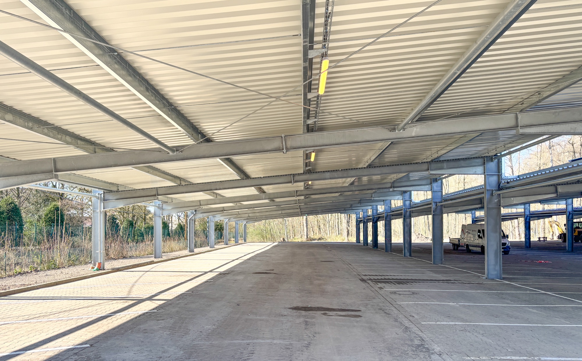 Solar-Carport vor einer Industriehalle mit Lkw und Pkw-Stellplätzen